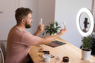 Ünlü blogcu. Video kaydederken kozmetik ürünlerini gösteren ve güzellik blogu için tavsiyelerde bulunan neşeli bir erkek vlogcu. Makyaj sanatçısı ve Güzellik vlog 'u