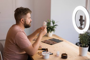 Sakallı adam profesyonel güzellik makyaj sanatçısı vlogger veya blog yazarı web sitesi veya sosyal medya paylaşımı için makyaj dersi kaydediyor