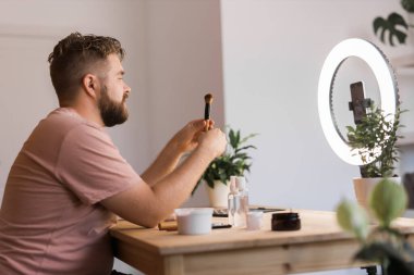 Portre sakallı adam Vlog gözden geçirme kozmetik ürünü ve kanal kayıt videosu hazırlıyor.