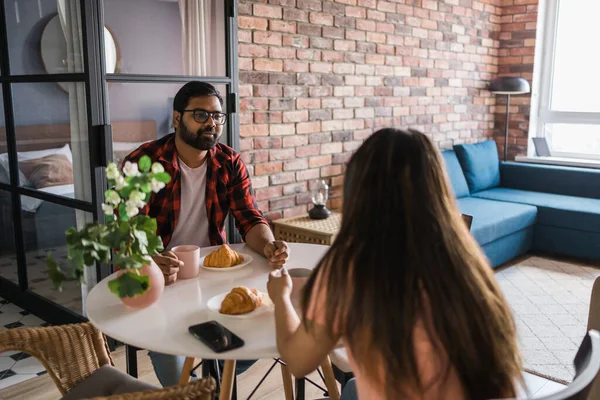 Young Diverse Loving Couple Eating Croissant Talks Together Home Breakfast — Stockfoto