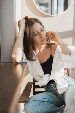 Happy young woman sit relaxing in comfortable chair feel peaceful enjoy sun near big windows. and smiling girl lying with eyes closed rest calm sunny morning at home.