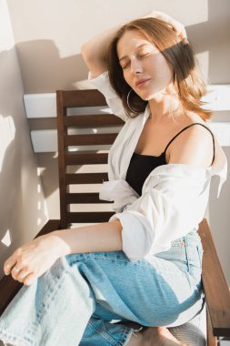 Pencerenin yanında, yüzünde çiçeklerin gölgesi olan güzel bir kadının portresi. Sabah ilkbahar estetiği