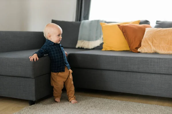 Caucasian baby newborn infant making first steps. Cute toddler kid child son boy learning walking creeping on living room. Childcare and childhood