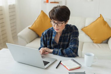 Businesswoman working on laptop computer sitting at home with a dog pet and managing her business via home office during Coronavirus or Covid-19 quarantine