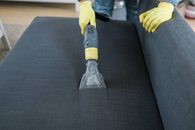 Man cleaning couch with washing vacuum cleaner