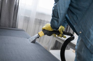Man cleaning couch with washing vacuum cleaner