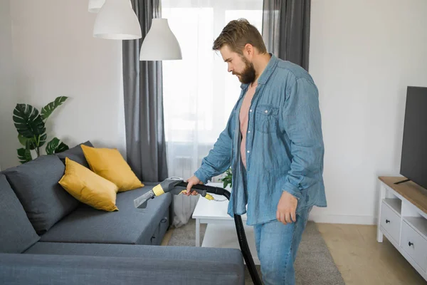 Stock image Man cleaning couch with washing vacuum cleaner