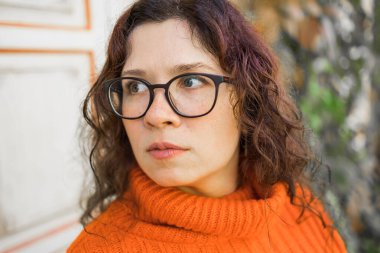 Portrait of carefree young woman smiling with urban background. Cheerful latin girl wearing eyeglasses in the city. Happy brunette woman with curly hair spectacles smiling.