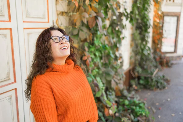 一个戴着时髦眼镜 穿着针织时髦橙色毛衣 背景树叶的漂亮年轻女子的秋天肖像 女孩在城里散步 — 图库照片
