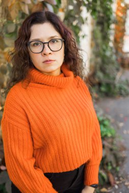 Portrait of carefree young woman smiling with urban background. Cheerful latin girl wearing eyeglasses in the city. Happy brunette woman with curly hair spectacles smiling.