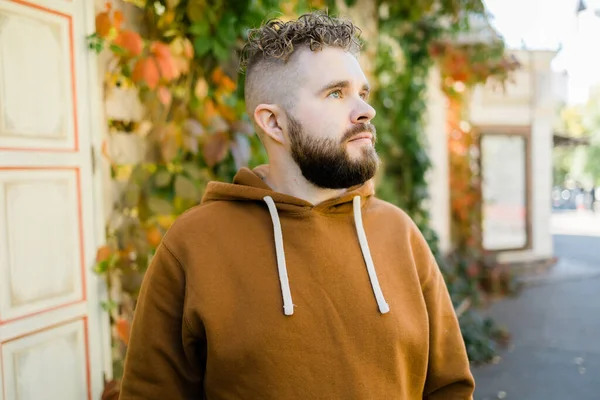 Close up shot of curly European male with beard wears switshot outdoors. Handsome man with crisp light hair