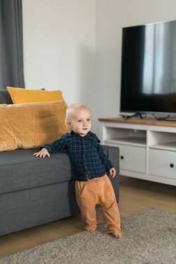 Caucasian baby newborn infant making first steps. Cute toddler kid child son boy learning walking creeping on living room. Childcare and childhood