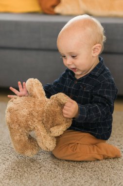 Mutlu çocuk oyuncak ayısıyla evde oynuyor. Çocukluk ve çocuk gelişimi aşamaları.