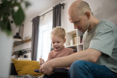 People with cochlear implant system. Kid study to hear with father, learning with video on tablet. Installation cochlear implant on child girl ear for restores hearing.