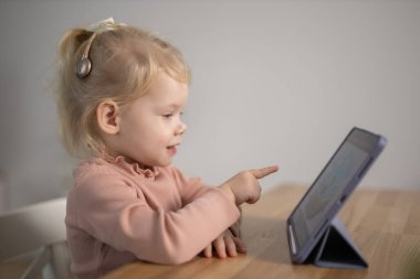 Deaf child girl with cochlear implant studying to hear sounds - recovery after cochlear Implant surgery and rehabilitation