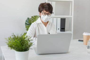 İş yerinde dizüstü bilgisayarda çalışan çekici, olgun bir iş kadını. Müdür ve ofis.