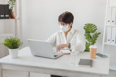 İş yerinde dizüstü bilgisayarda çalışan çekici, olgun bir iş kadını. Müdür ve ofis.