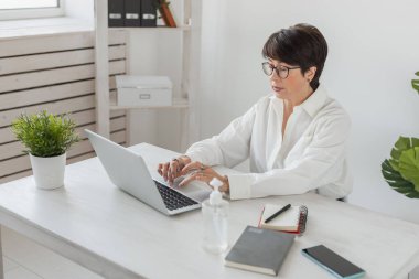 İş yerinde dizüstü bilgisayarda çalışan çekici, olgun bir iş kadını. Müdür ve ofis.