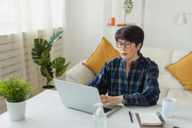 Businesswoman working on laptop computer sitting at home with a dog pet and managing her business via home office during Coronavirus or Covid-19 quarantine