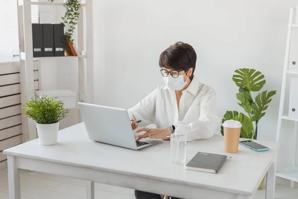 Stock image Attractive mature business woman working on laptop in her workstation - manager and office