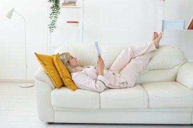 Göz kamaştırıcı bir kadın pijama giyer ve mutlu bir gülümseme ile sabahları ürperir. Pozitif kadın model ev kıyafetleri ve evde boş zaman tatili.