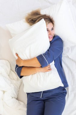 Güzel sarışın kadın sabah uyanır ve yatakta uzanır, genç kadın yeni günü selamlar.