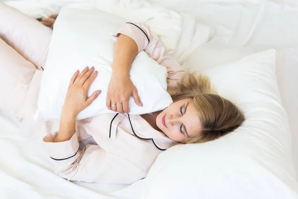 stock image Beautiful blonde female is waking up in morning and stretches in Bed, young woman greets new day