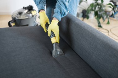 Man cleaning couch with washing vacuum cleaner