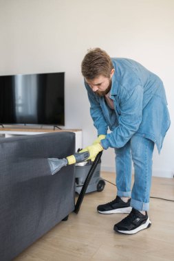 Man cleaning couch with washing vacuum cleaner