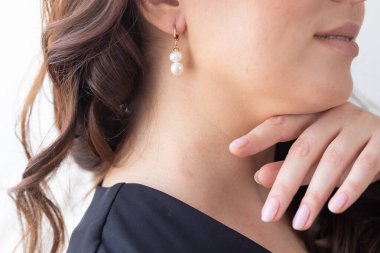 Cazibe ve güzellik, mücevher ve lüks - İnci küpeli güzel kadın yüzüne yakın çekim
