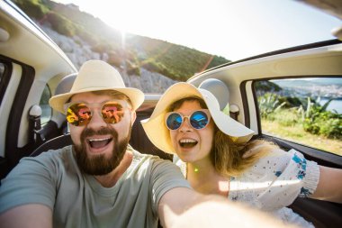 Romantik çift, okyanus ya da deniz kıyısındaki kiralık Cabrio arabasında akıllı telefon kamerasıyla selfie çekiyor, yaz tatilinin tadını çıkarıyor ve hafta sonları deniz kenarında cep telefonuyla dinlenirken fotoğraf çekiyor.