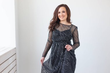 Beyaz odada poz veren siyah giysili güzel bir bayan. Lüks hayat tarzı olan insanlar.