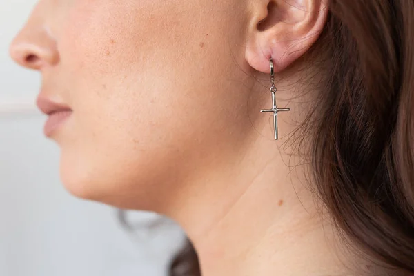 Elegant woman with silver cross earrings. Female jewelry and accessories concept