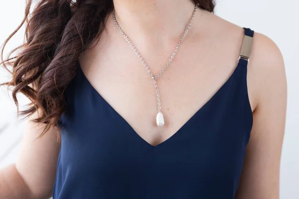 Close-up woman wearing luxury pearl pendant and gold necklaces - jewellery and accessories
