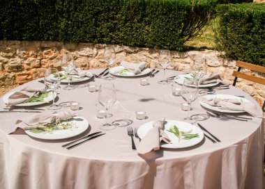 Şehirde güzel bir açık hava düğün dekorasyonu. Mumlar, kurumuş çiçekler, buketli aksesuarlar, masa başında bardaklar, çimenlikteki yeni evliler masasında keten masa örtüsü.