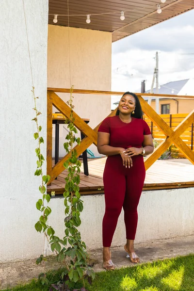 stock image African american woman relaxing and enjoying sun while standing at terrace or balcony at sunlight at summer. Slow living and tranquil moment and mental health. Backyard terrace vacation weekend