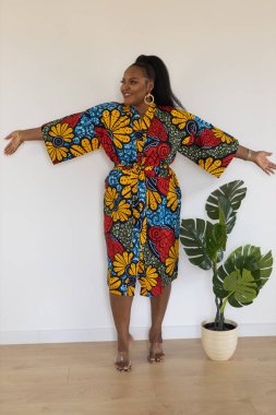 Gülümseyen Afro-Amerikan genç bayan, beyaz arka planda duran şık elbiseler giyer - kapsama ve çeşitlilik