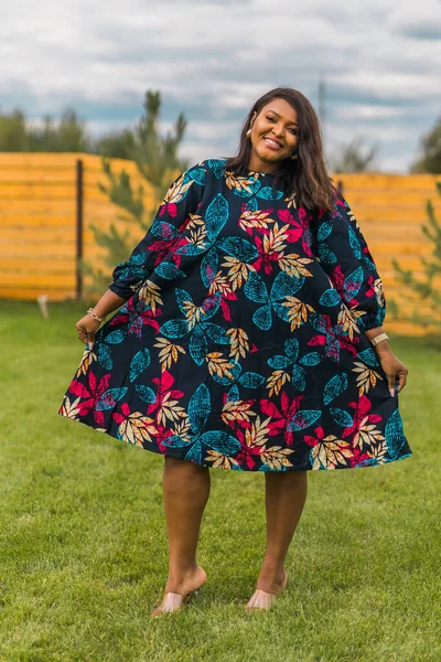 stock image Summer portrait of beautiful african american woman in red casual wear standing on backyard. Suburban lifestyle and chilling on weekend in countryside concept