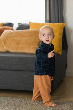 Kafkasyalı yeni doğmuş bebek ilk adımlarını atıyor. Küçük tatlı çocuk. Oğlan çocuğu. Oturma odasında yürümeyi öğreniyor. Çocuk bakımı ve çocukluk