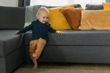 Kafkasyalı yeni doğmuş bebek ilk adımlarını atıyor. Küçük tatlı çocuk. Oğlan çocuğu. Oturma odasında yürümeyi öğreniyor. Çocuk bakımı ve çocukluk