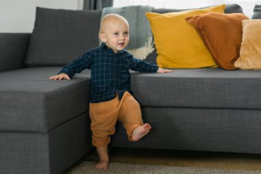 Caucasian baby newborn infant making first steps. Cute toddler kid child son boy learning walking creeping on living room. Childcare and childhood