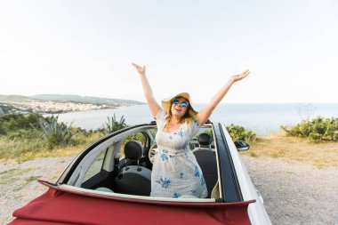 Cabrio 'da deniz ve kumsala karşı eğlenen genç bir kadın. Seyahat ve yaz seyahati.