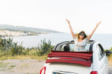 Cabrio 'da deniz ve kumsala karşı eğlenen genç bir kadın. Seyahat ve yaz seyahati.