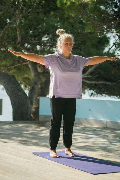 Stock image Mature woman with dreadlocks working out doing yoga exercises on sea beach - wellness well-being and active elderly age