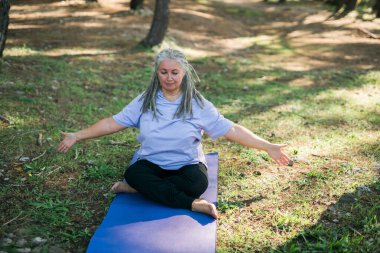 Deniz kenarında yoga ve tai chi yapan olgun yaşlı bir kadın. Refah ve sağlık kavramı.