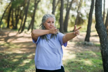 Deniz kenarında yoga ve tai chi yapan olgun yaşlı bir kadın. Refah ve sağlık kavramı.