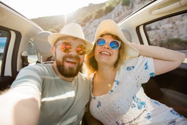 Mutlu ve güzel bir çift tatilde üstü açık bir arabayla selfie çektiriyorlar. Kiralık arabalar ve tatil konsepti