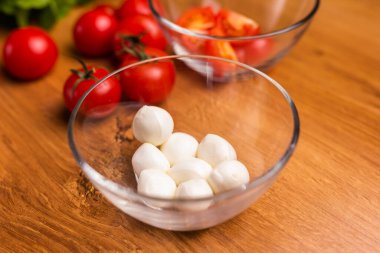 Bowl of small mozzarella balls in kitchen, top view.