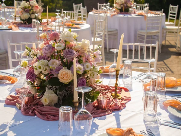 Wedding. Banquet. The chairs and round table for guests, served with cutlery, flowers and crockery and covered with a tablecloth