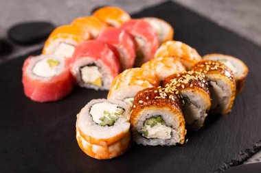 Karanlık arka planda suşi yuvarlanıyor. Japon ve Asya yemekleri